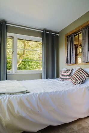 A bedroom with a bed, a window, and curtains. - Vintage charm, giant yard & hot tub in "The Creek" (Roberts Creek)