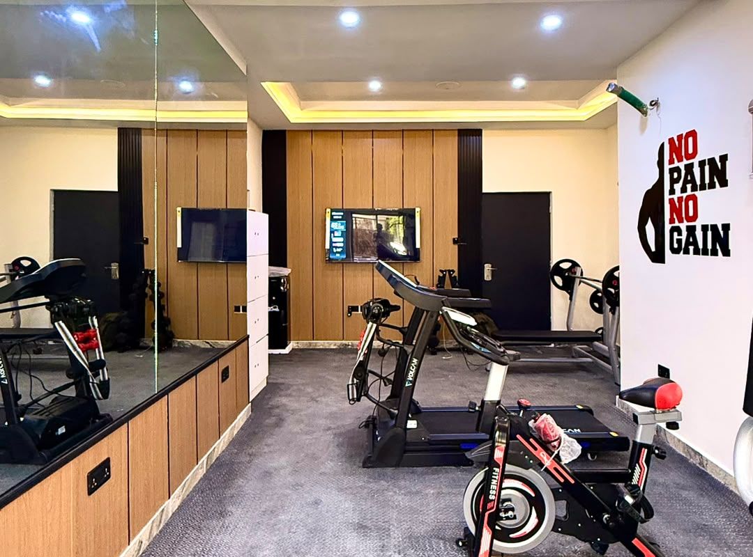 Un gimnasio con equipo de ejercicio, televisión y decoración de pared motivacional.