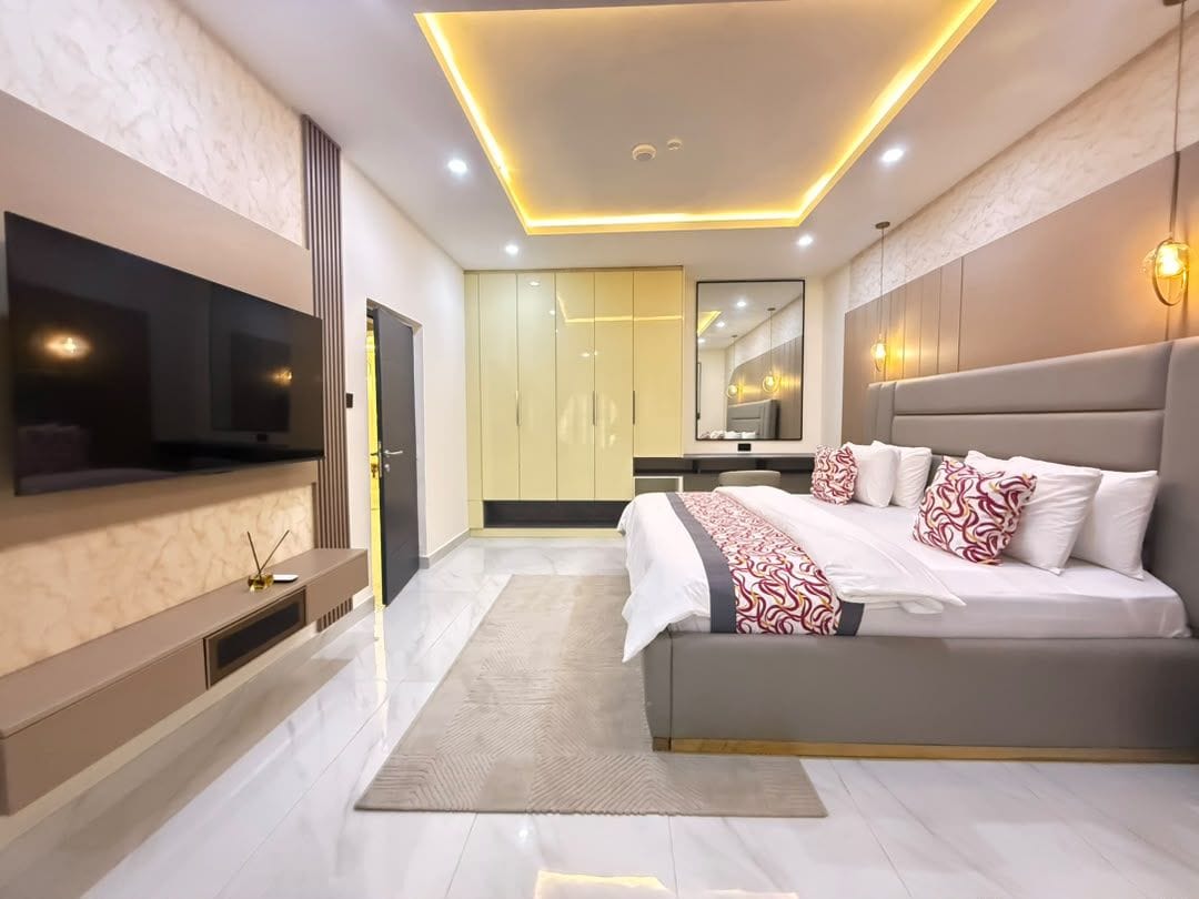 Un dormitorio moderno con una cama grande, un televisor de pantalla plana y un vestidor.