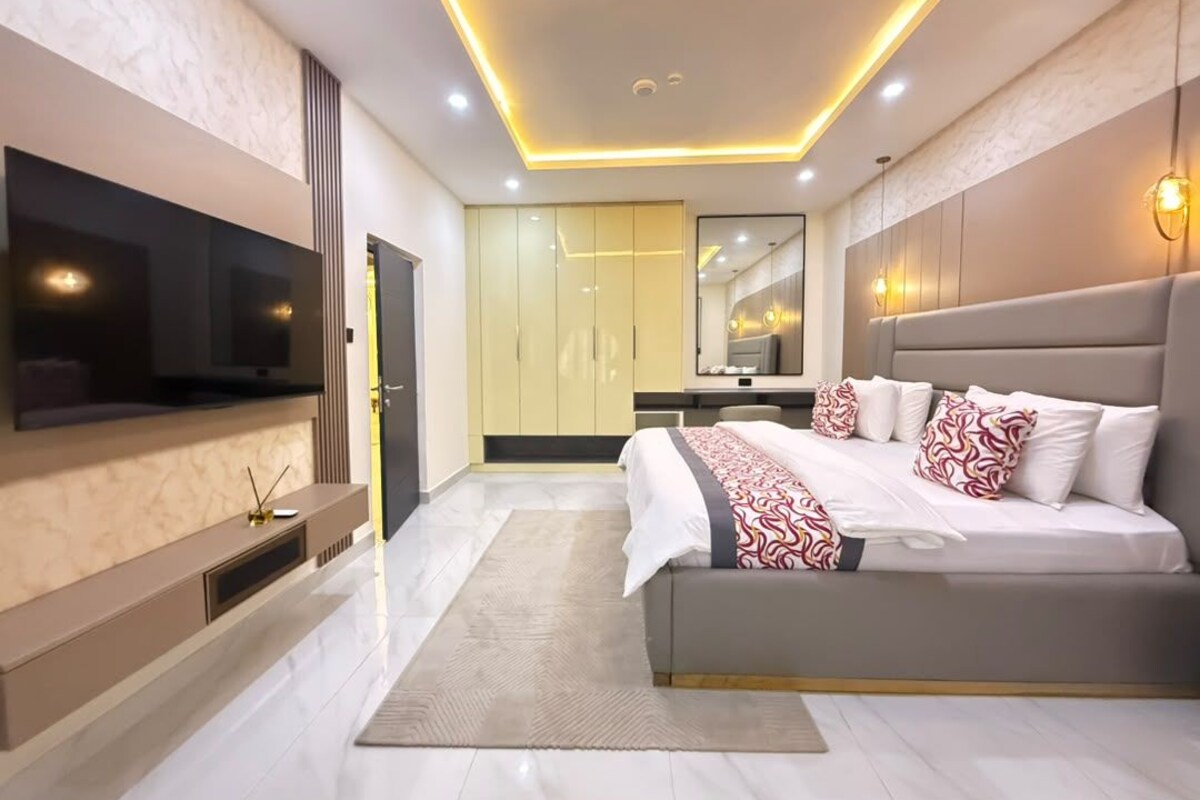 Een moderne slaapkamer met een groot bed, een flatscreen-tv en een inloopkast.