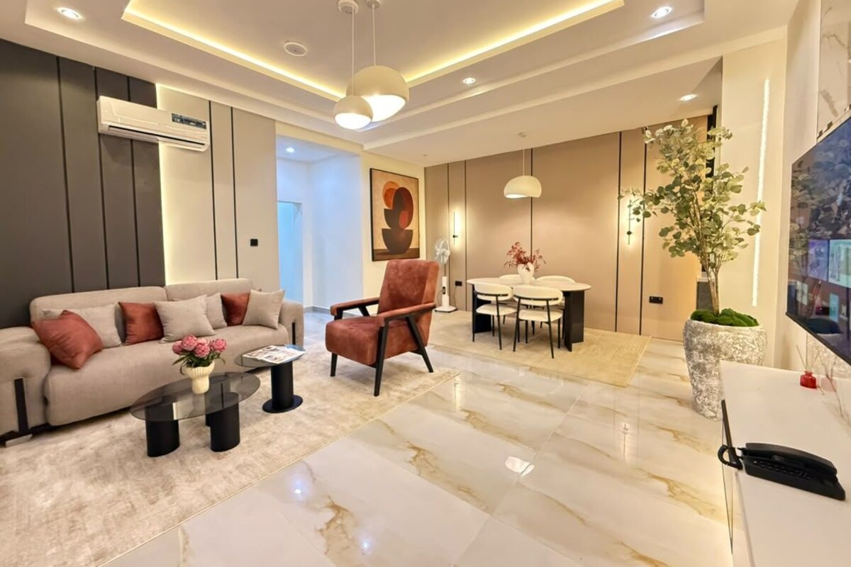 Een moderne woonkamer met een bank, fauteuil, salontafel en een eethoek.