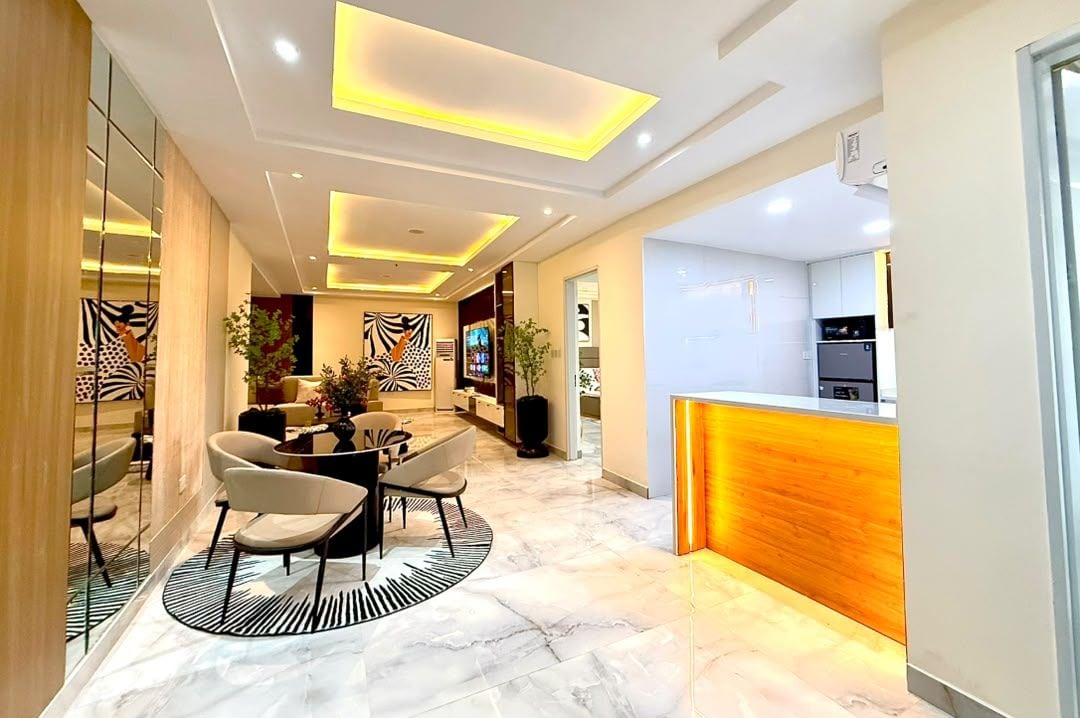 Un interior moderno con zona de comedor que incluye una mesa redonda y sillas, cocina con encimera de madera y mostrador de recepción.