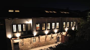 Un edificio de varios pisos con numerosas ventanas, paredes de piedra y un balcón.