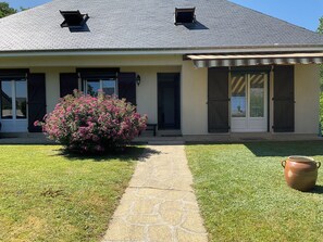 A house with a stone pathway leading to the entrance, a large bush with pink flowers, and a clay pot on the lawn. - New Listing (Égletons)