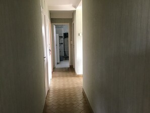 A hallway with a herringbone floor leading to a room with a closet and a radiator. - New Listing (Égletons)