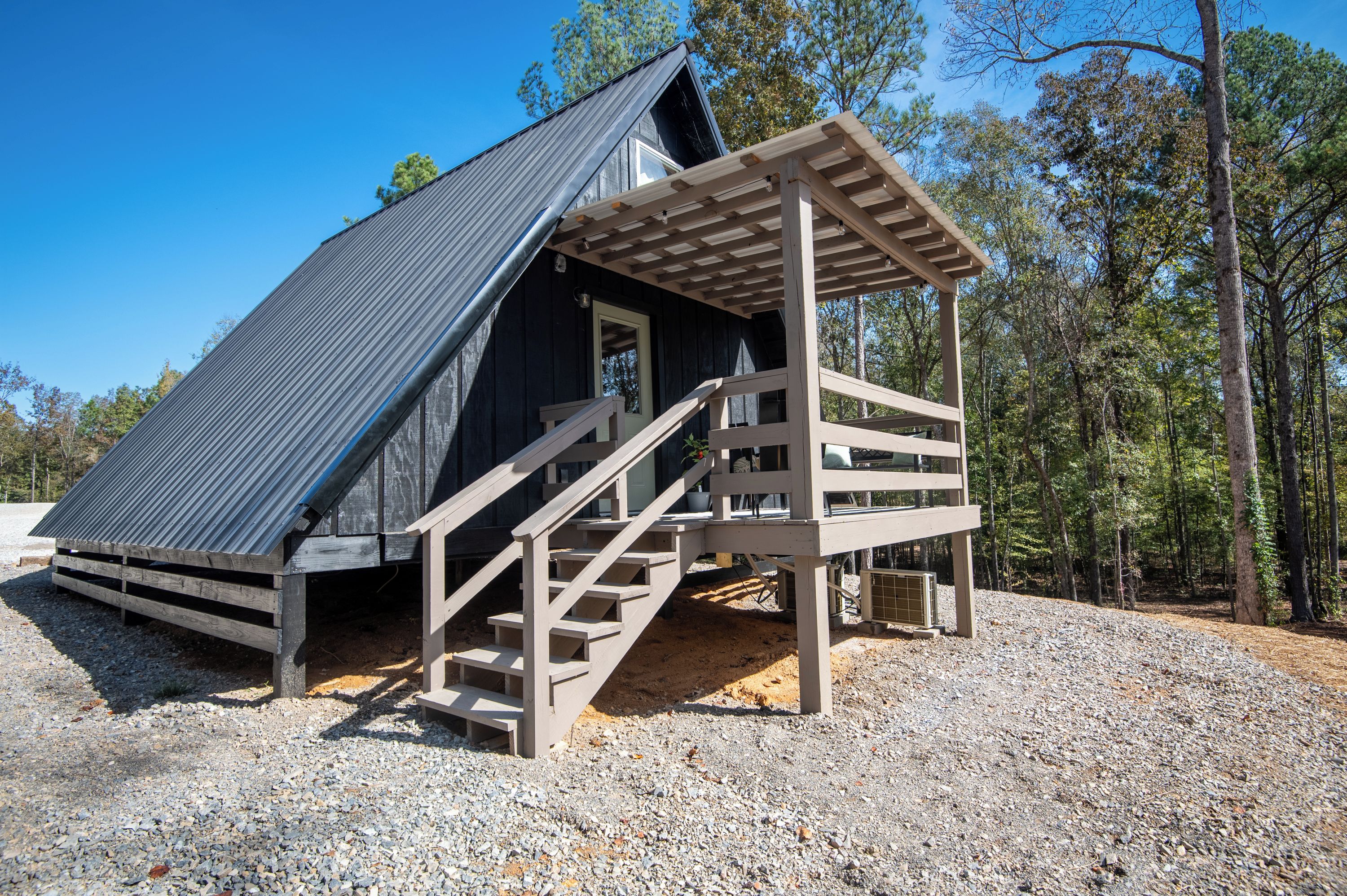Eine Holzhütte mit geneigtem Dach und einer Holztreppe, die zu einer Veranda führt.