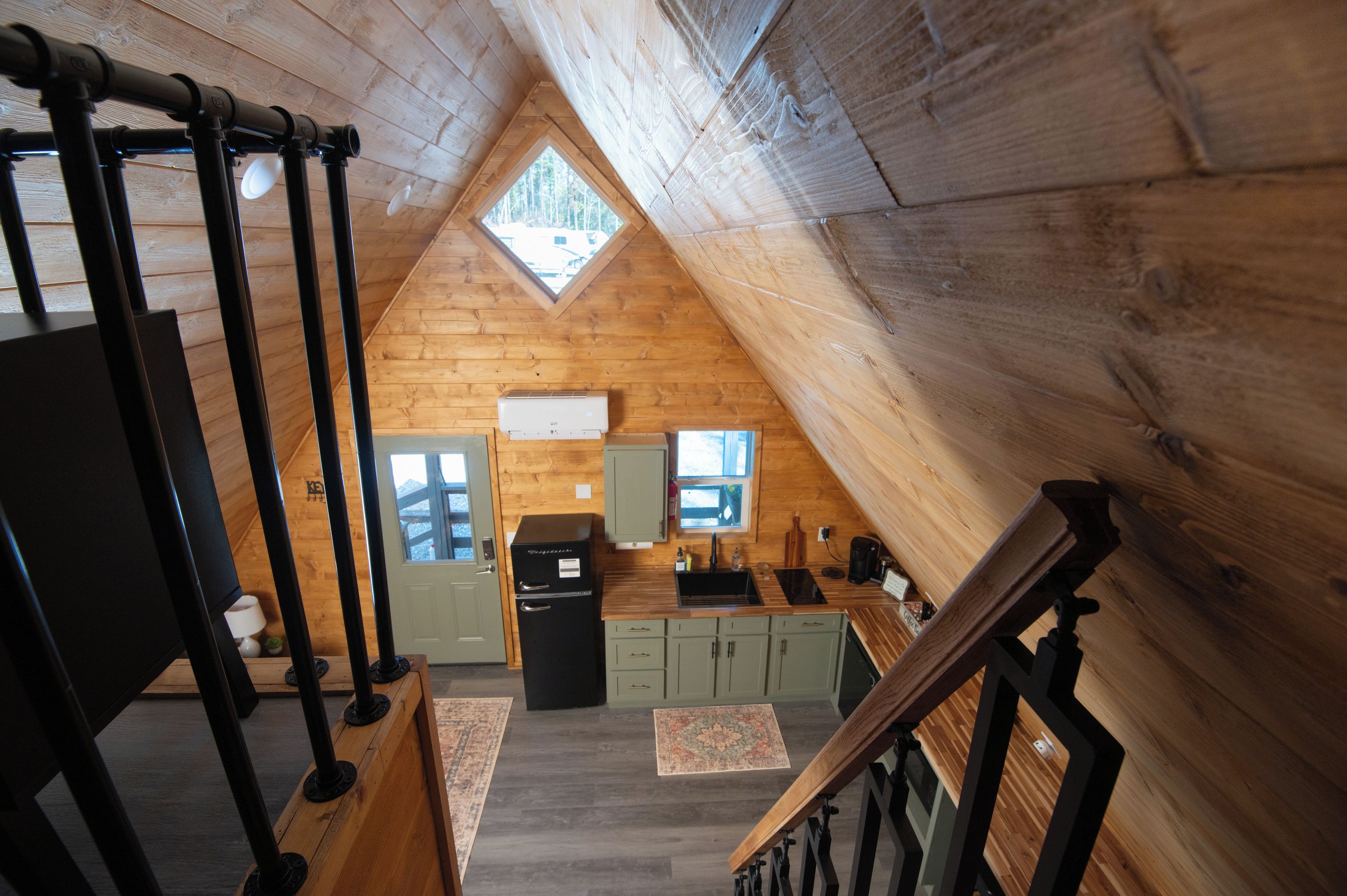 A wooden interior with a kitchen, a dining area, and a staircase.