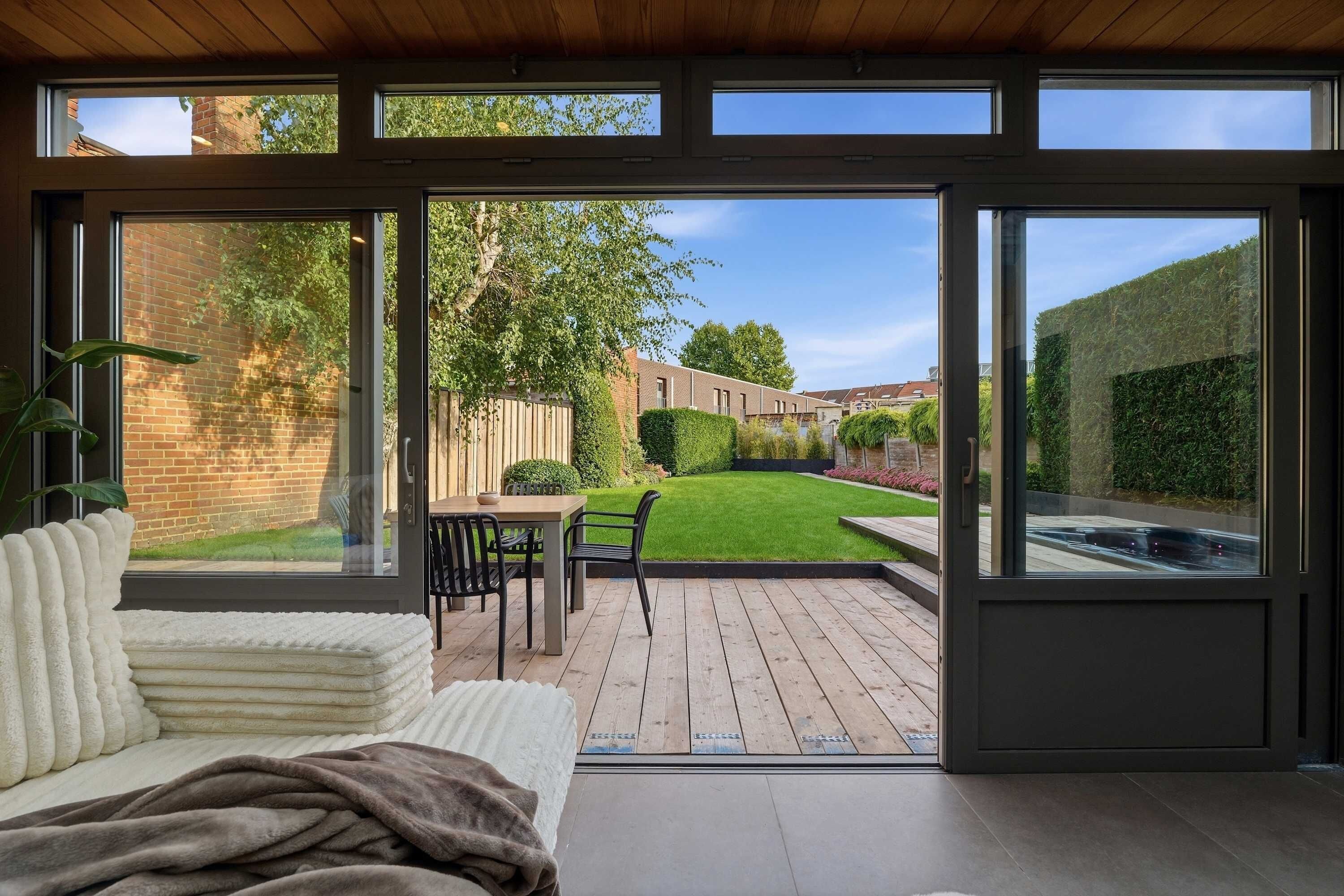 A modern interior with a view of a well-maintained garden and a swimming pool.