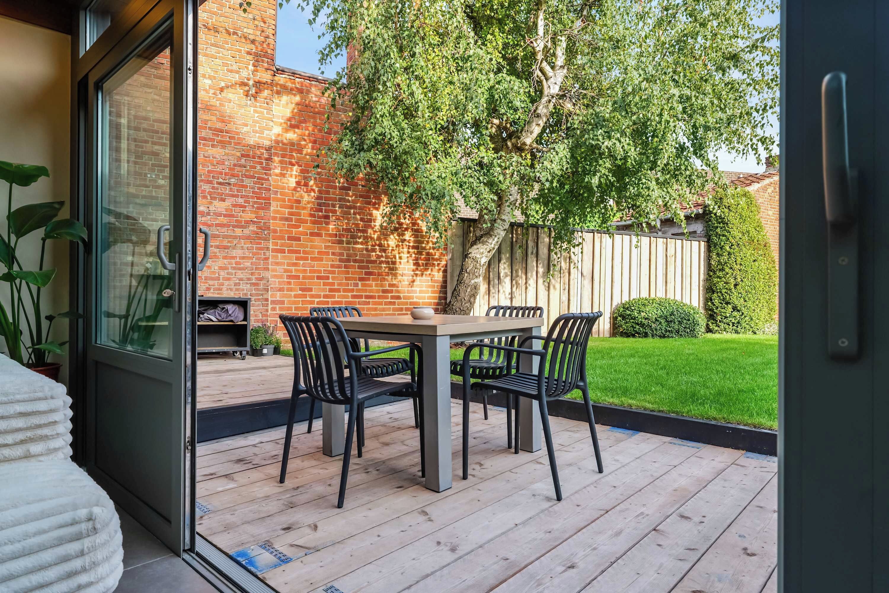 A patio with a table and chairs, a brick wall, and a wooden fence.