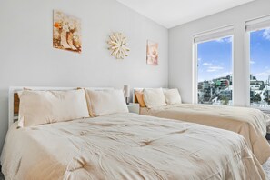 A hotel room with two beds, a large window, and artwork on the walls. - NV Hotel w/ Pool, Gym, Rooftop Lounge & Free Park (Nashville)