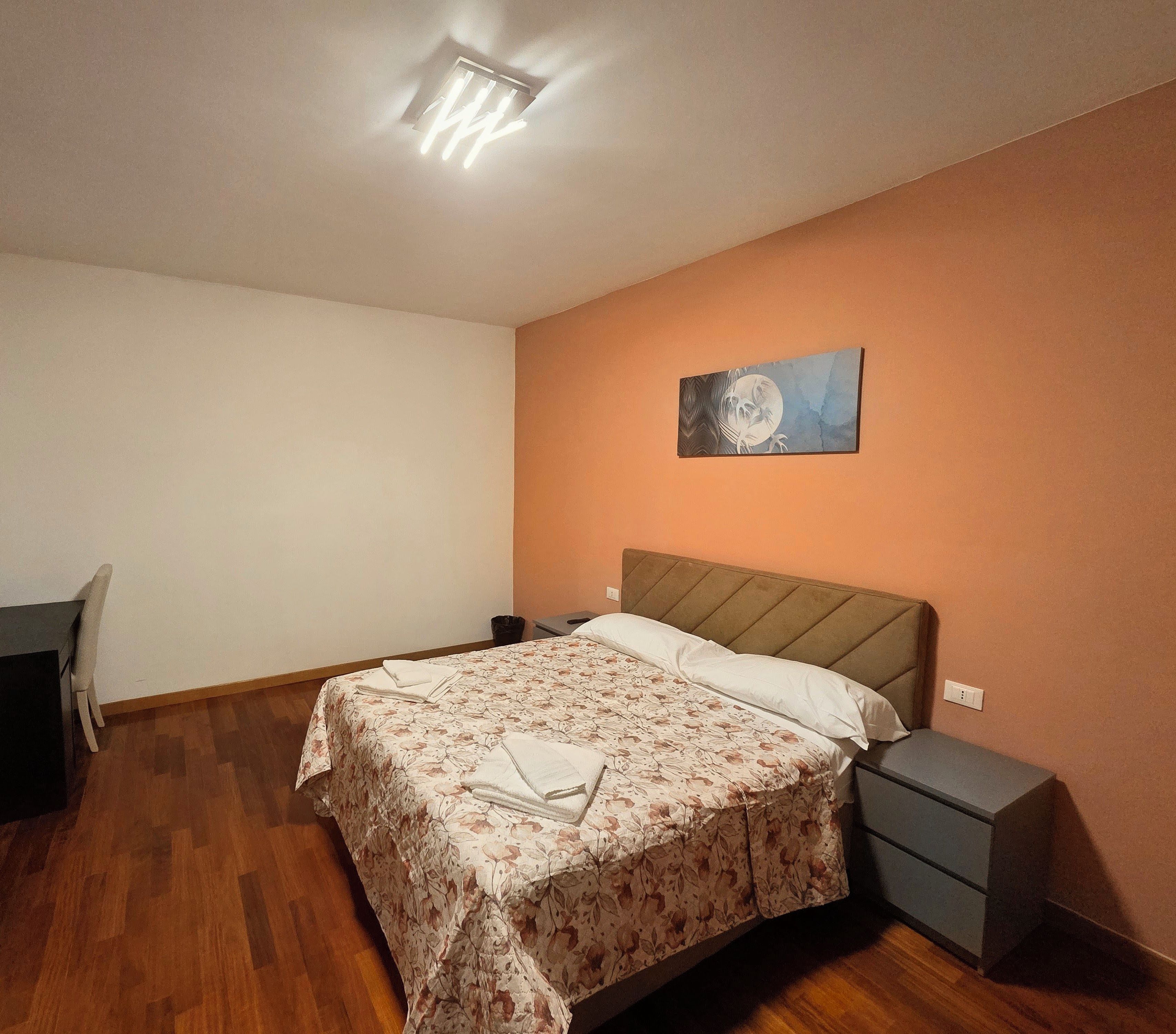 Ein Schlafzimmer mit einem Bett, Nachttischen, einem Sessel und einem Bild an der Wand.