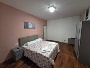 Une chambre à coucher avec un lit, une table de chevet, une armoire et un tableau au mur.