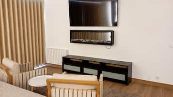 A modern living room with a flat-screen TV, a console table, a sofa, and a patterned rug.