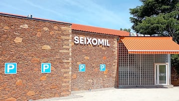 A building with a stone facade and a sign that reads 'SEIXOMIL'. There are four parking signs on the wall.