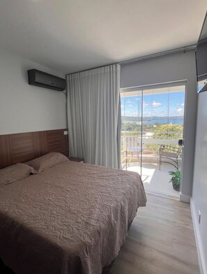 A bedroom with a large bed, a sliding glass door to a balcony, and a view of the outdoors. - New Listing (Caldas Novas)