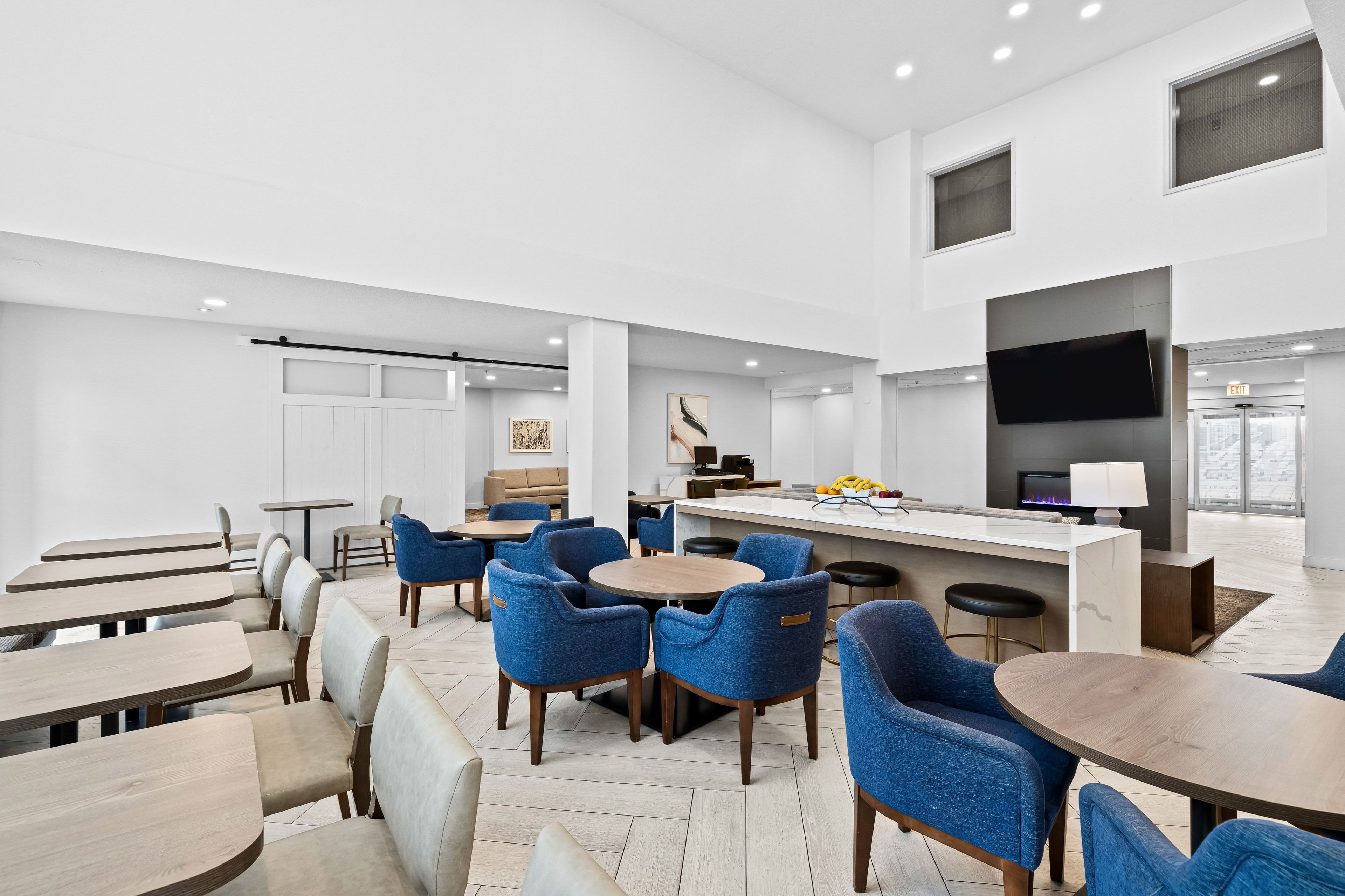 A modern, well-lit dining area with blue upholstered chairs and wooden tables.