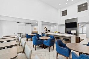 Un comedor moderno y bien iluminado con sillas tapizadas en azul y mesas de madera.