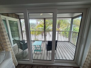 Une pièce dotée d’une porte-fenêtre coulissante donnant sur une terrasse extérieure avec une table et des chaises.