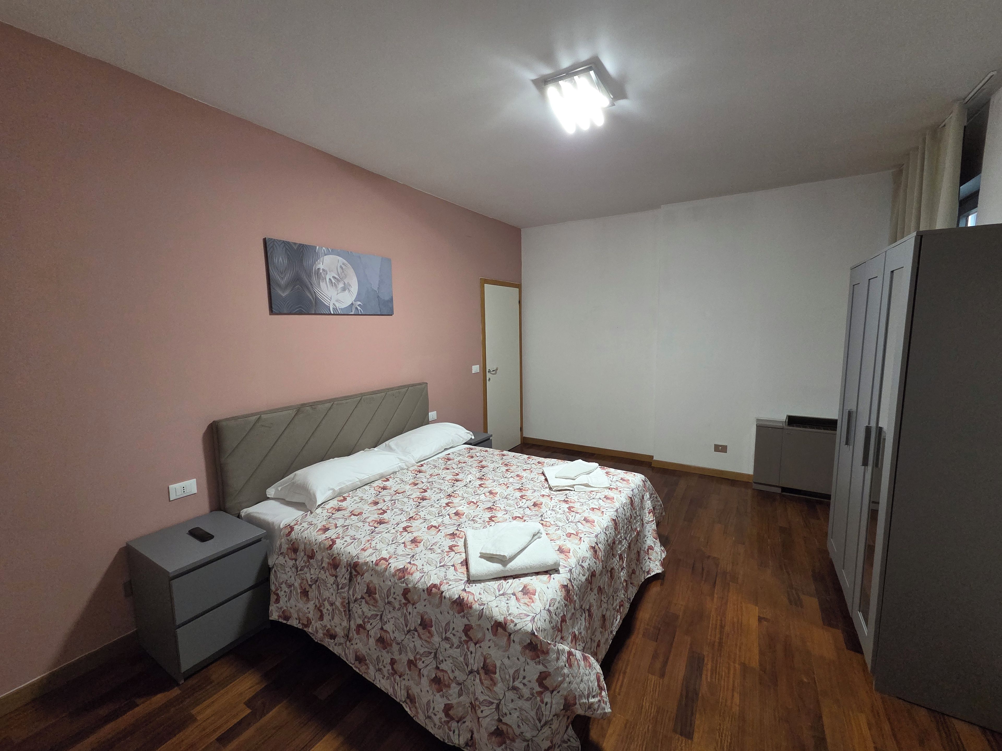 Ein Schlafzimmer mit Bett, Nachttisch, Kleiderschrank und einem Bild an der Wand.