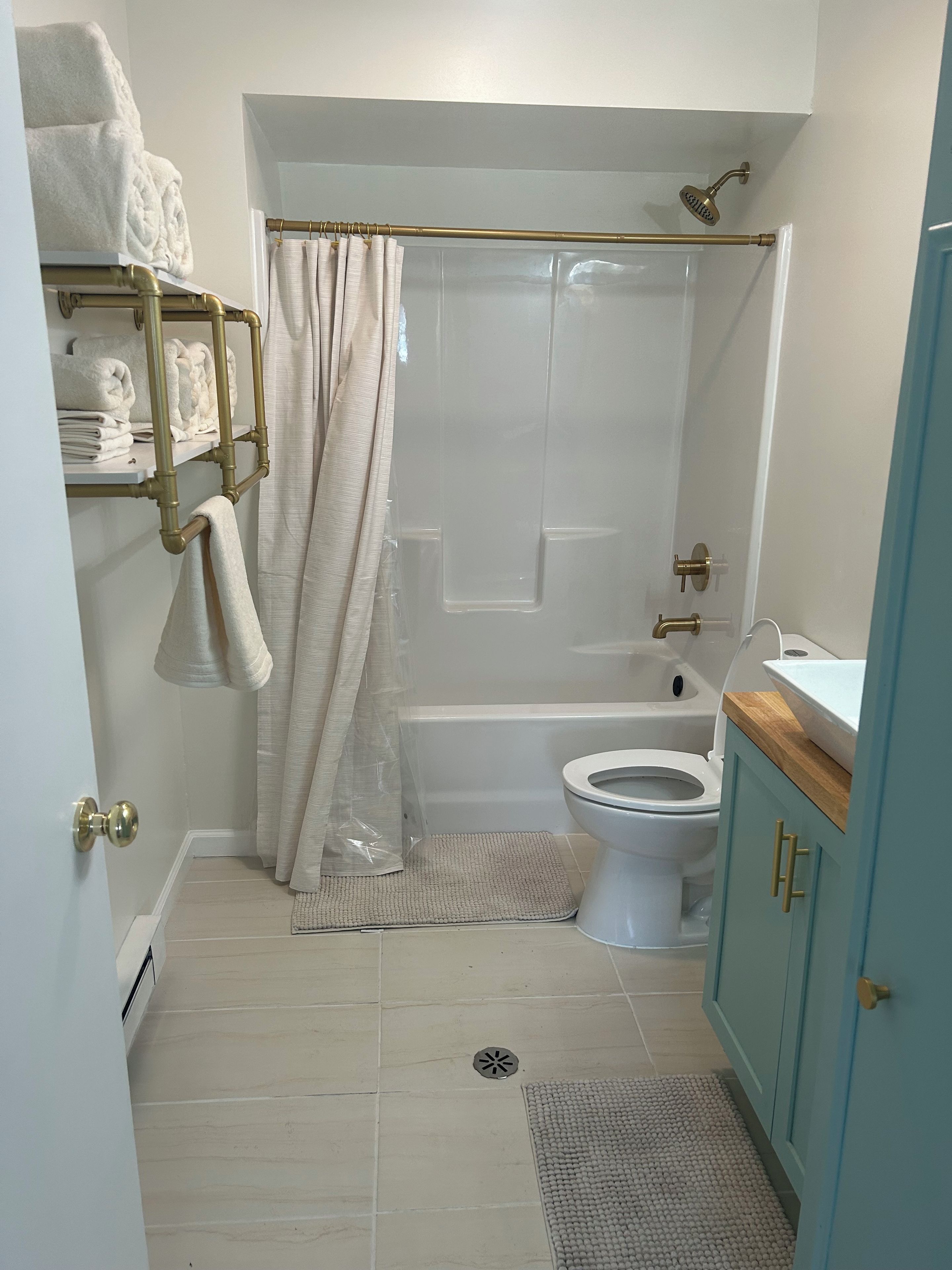 A bathroom with a bathtub, toilet, and a towel rack with folded towels.