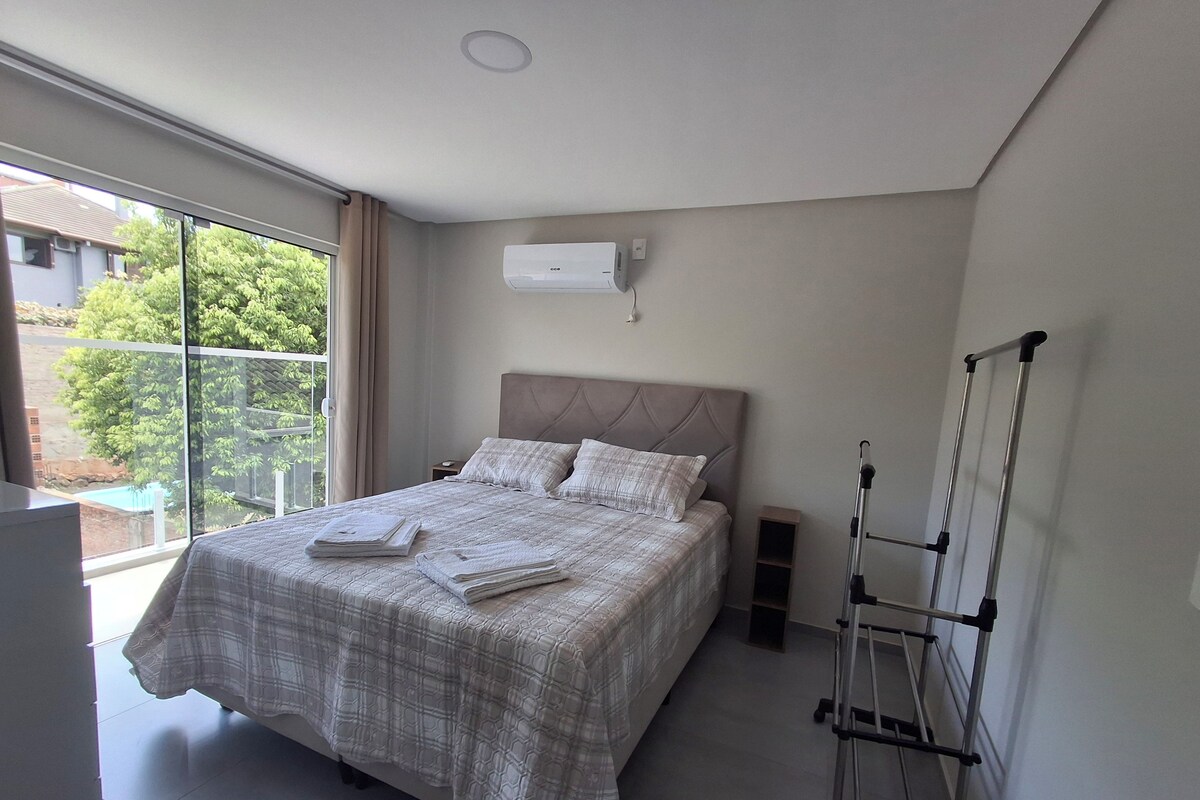 Un dormitorio con cama, ventana y aire acondicionado de pared.