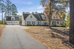 Une maison à deux étages avec un garage, une véranda et une allée menant à l’entrée principale.