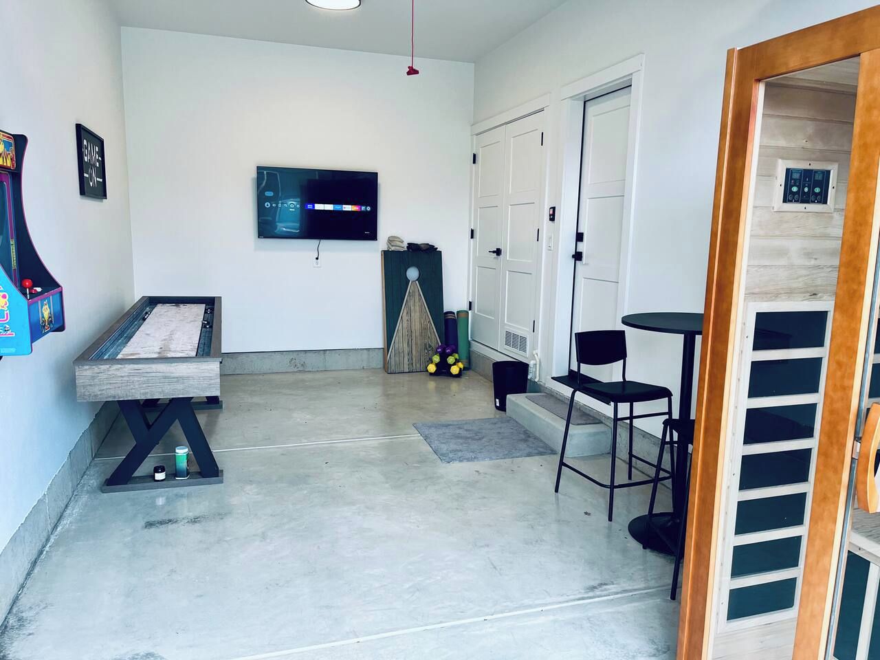 A room with a billiards table, a television mounted on the wall, and a door leading to a closet.