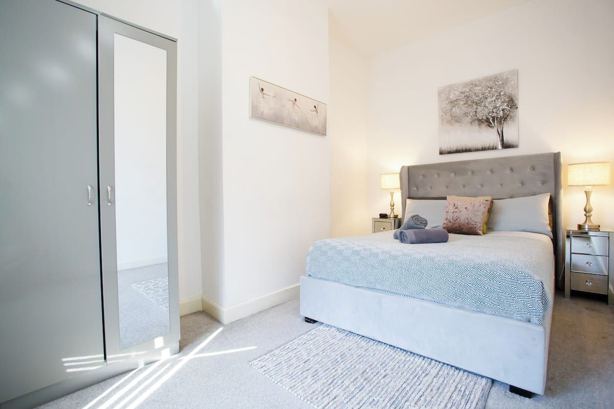 A bedroom with a bed, nightstands, a wardrobe, and artwork on the walls.