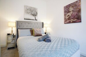 A neatly made bed with a patterned bedspread, a headboard, and two bedside lamps. - 2BR House Nr Etihad l Parking/Garden/Pool Table (Manchester)