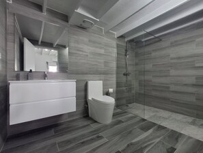 Une salle de bain moderne avec une douche à parois de verre, un meuble-lavabo blanc et des toilettes.