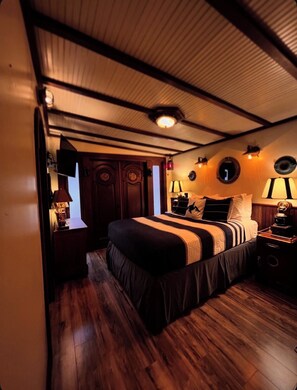 Une chambre avec un lit, des lampes de chevet, un plancher en bois et un plafond avec des poutres apparentes.