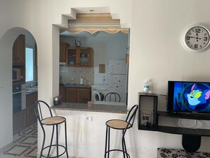 A compact living space with a kitchen area, a dining table with two chairs, and a television. - New Listing (Djerba Midun)
