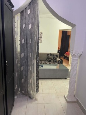 A living room with a sofa, a coffee table, and a decorative pillar. - New Listing (Djerba Midun)