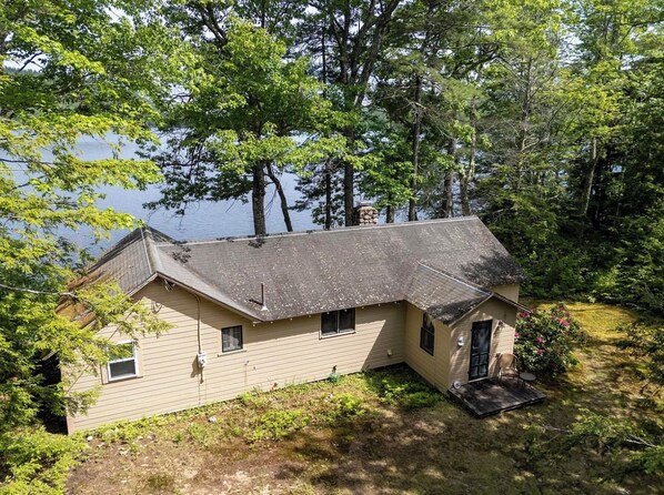 A single-story house with a sloped roof, a front porch, and a small deck. - Soothing 2-bedroom cabin in charming Stoneham; perfect for a getaway (Stoneham)