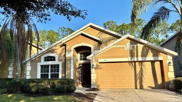A residential house with a garage, a driveway, and a well-maintained lawn.
