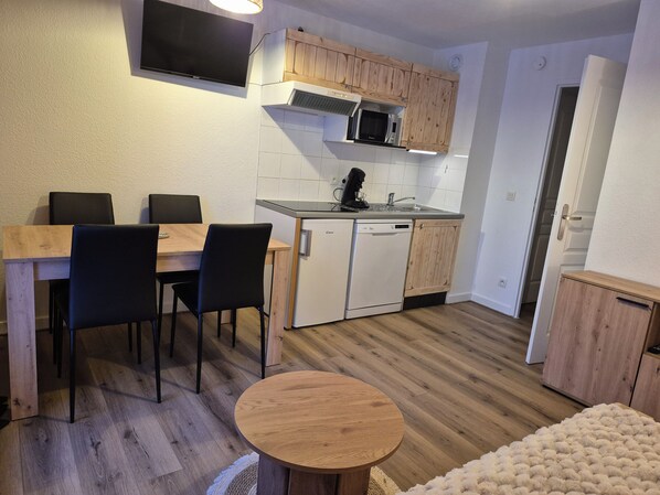 Une cuisine compacte comprenant une table à manger, des chaises, un four à micro-ondes et un lave-vaisselle.