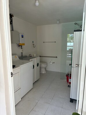 Un bagno con un WC, una lavatrice, una doccia e un asciugamani ad aria.