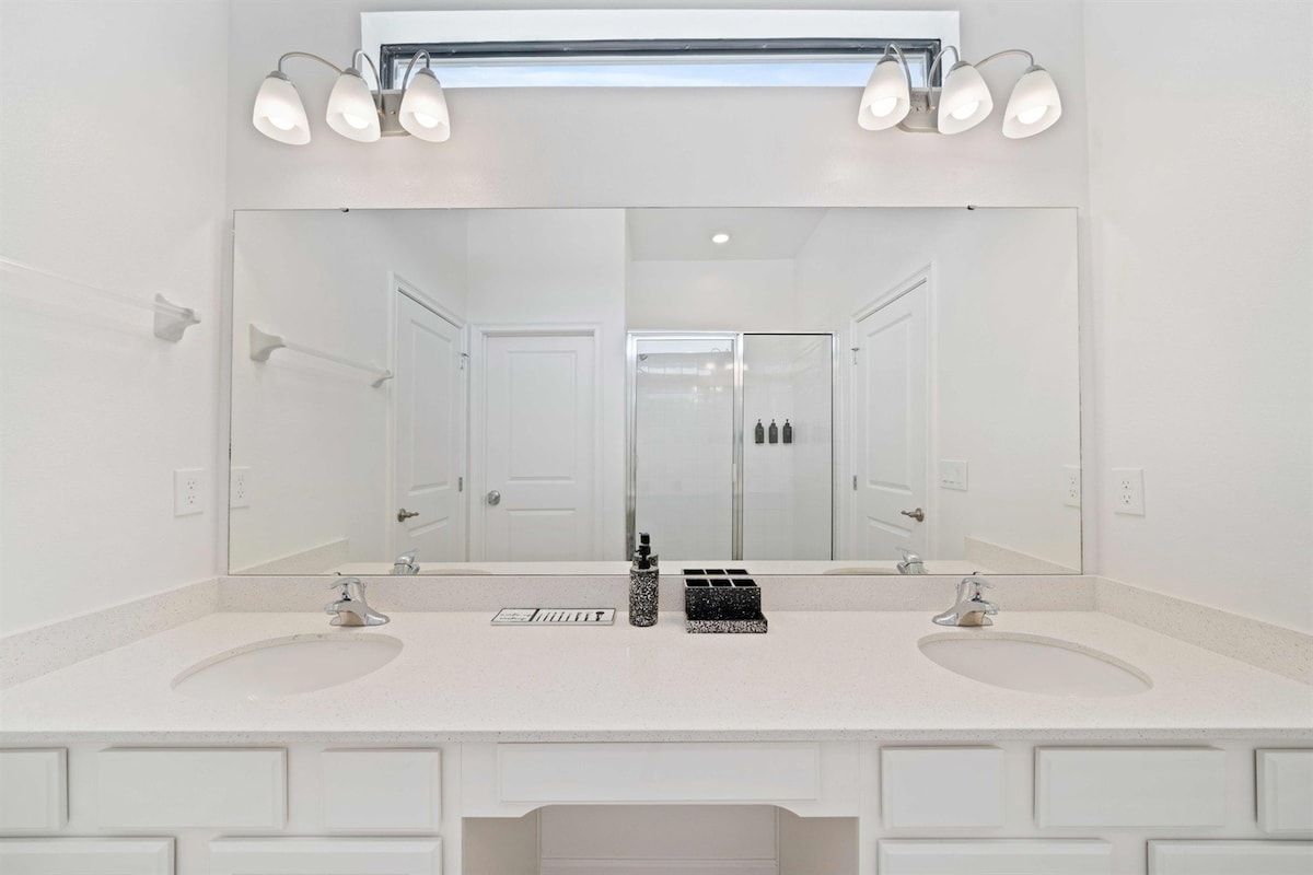 A bathroom with two sinks, a large mirror, and a lighted vanity.