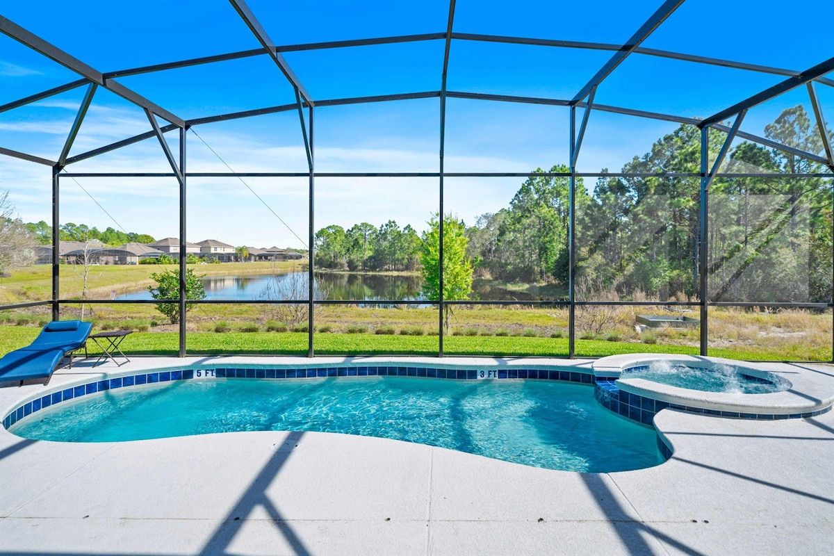 A swimming pool with a hot tub, surrounded by a covered area with a view of a lake and trees.