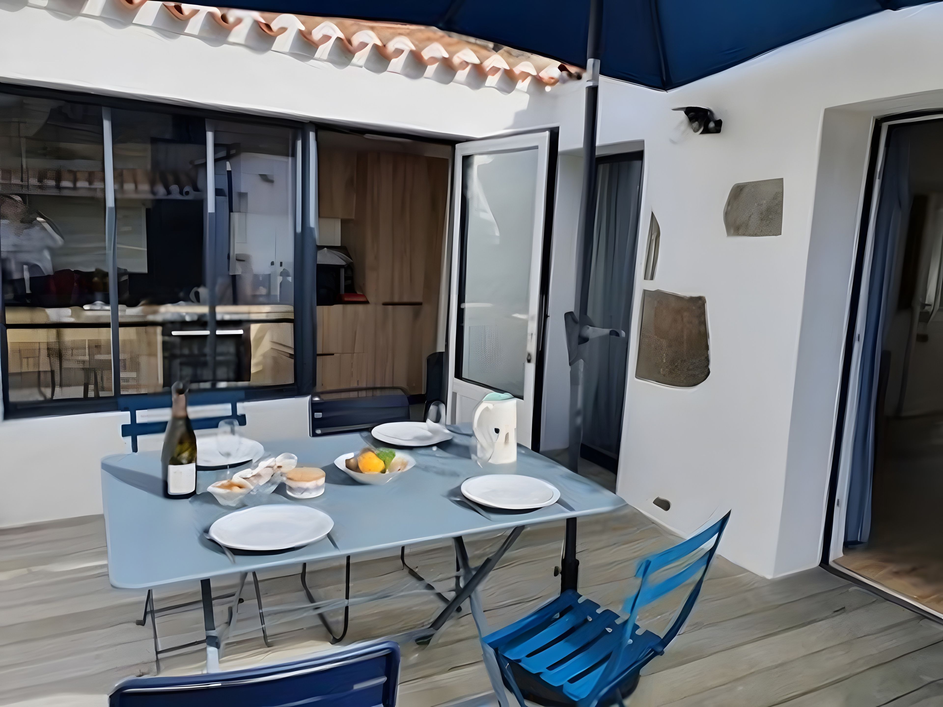 An outdoor dining area with a table set for two, a bottle of wine, and a chair.
