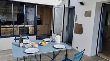 An outdoor dining area with a table set for two, a bottle of wine, and a chair.