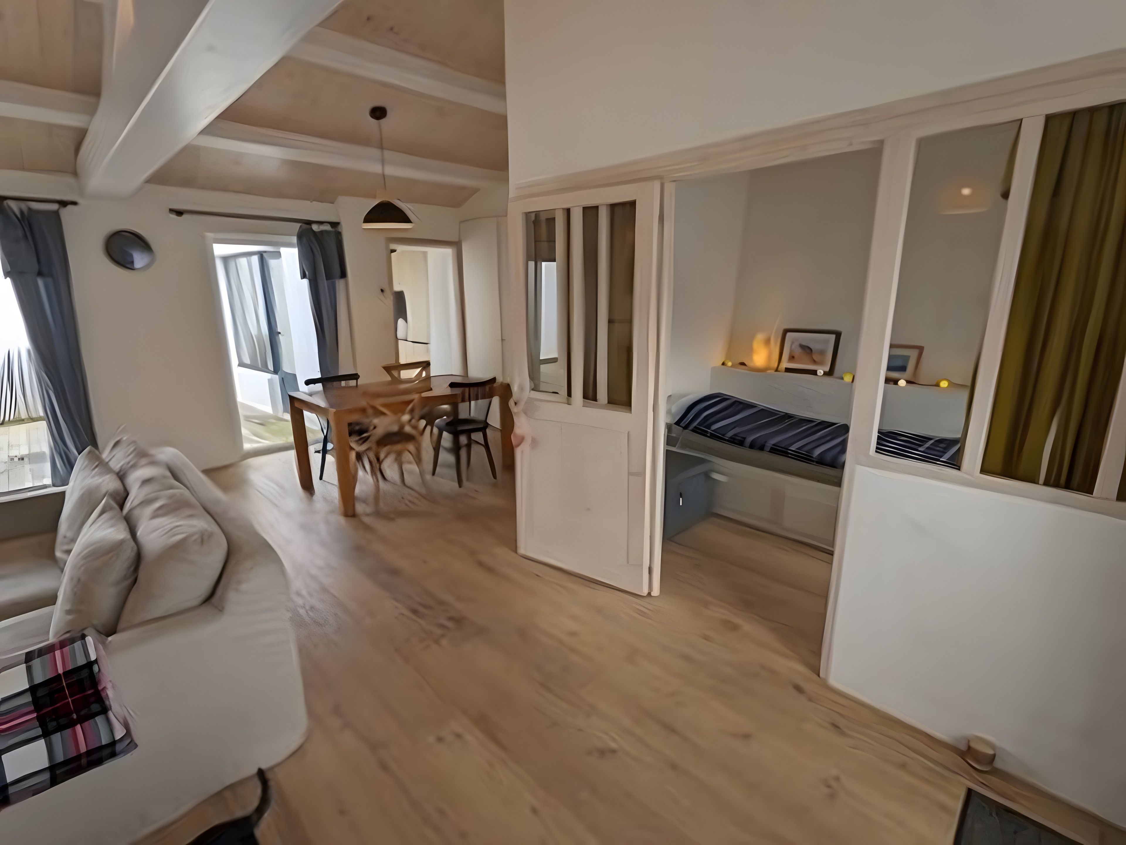 A modern interior with a dining area, a sofa, and a bed.