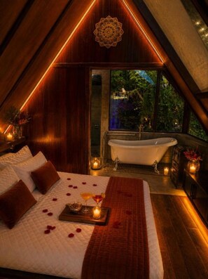 A bedroom with a large bed, a bathtub, and a view of greenery outside. - Chamánica Ecolodge, Coroico - Habitación Doble con vistas a la montaña (coroico)