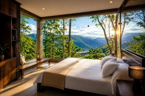 Ein Schlafzimmer mit einem großen Bett, einer Sitzecke und Blick auf Berge und Bäume.