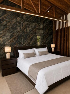 Ein Schlafzimmer mit einem großen Bett, einem Holz-Kopfteil, einer Marmorwand und zwei Nachttischlampen.