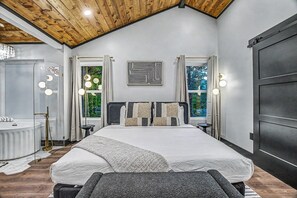 Une chambre avec un grand lit, une coiffeuse avec des miroirs et une vue sur la verdure environnante.
