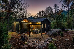 Une cabane dotée d’une terrasse, d’un foyer extérieur et d’un espace extérieur couvert.