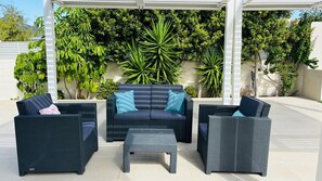 Ein Sitzbereich im Freien mit zwei Sofas, zwei Sesseln, einem kleinen Tisch und einer Pergola.