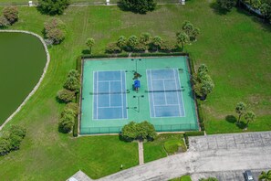 Vista aèria d'una pista de tennis amb vegetació circumdant i una massa d'aigua.