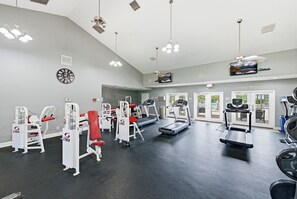 A gym with various exercise equipment, a clock, and a television on the wall. - One Bedroom overlooking the water with gym, pickleball, pool, and hot tub (St. Petersburg)